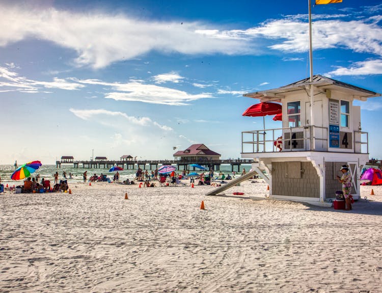 Beachgoers enjoy the summer sun at Clearwater Beach, Florida, with a scenic pier and lifeguard station.